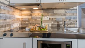 Une cuisine au design moderne, dotée d’un pare-feu en bois, d’appareils électroménagers en acier inoxydable et d’un évier encastré.