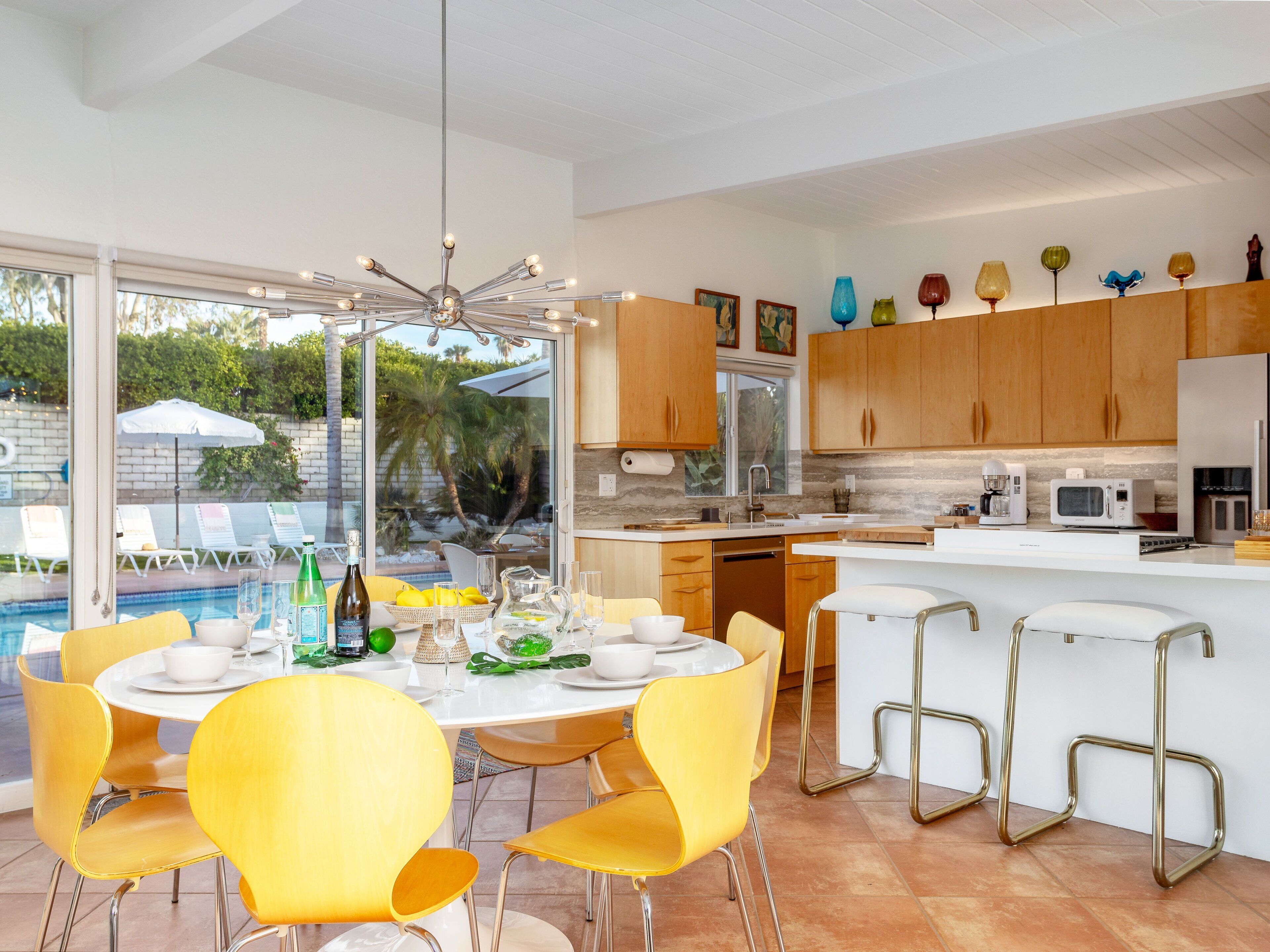 A modern kitchen with a dining area, a poolside view, and a variety of kitchen appliances.