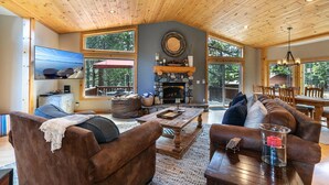 Una sala de estar acogedora con chimenea, techo de madera y ventanas amplias.