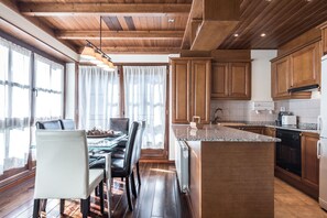Een moderne keuken met houten kastjes, een granieten aanrecht en een eethoek met een glazen tafel en stoelen.
