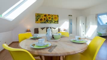 Un comedor con una mesa redonda de madera, sillas amarillas y un cuadro de un girasol en la pared.