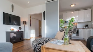 Ein modernes Wohnzimmer mit einem zebra-gemusterten Sofa, einem Holztisch und einem an der Wand befestigten Flachbildfernseher.