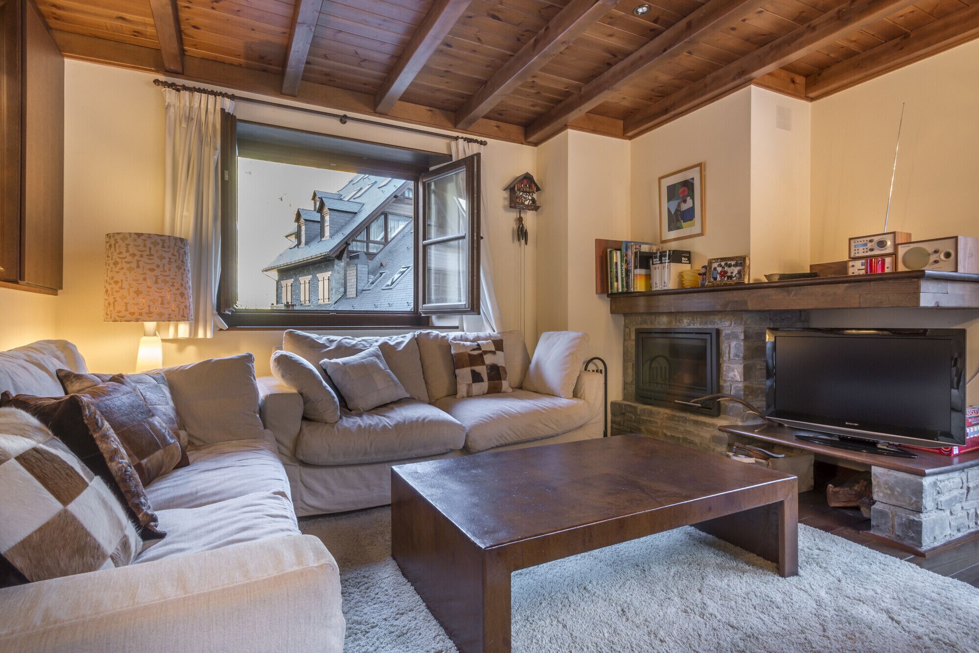 Una sala de estar acogedora con un sofá, una mesa de centro, una chimenea y un televisor.