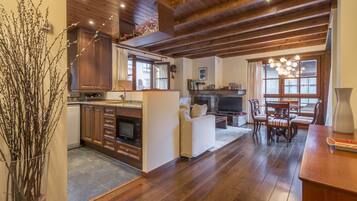 Un salón espacioso con chimenea, una mesa de comedor y una cocina con armarios de madera y encimera de piedra.