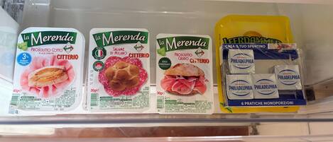 A refrigerator shelf with three packages of La Merenda salami and a box of Philadelphia cheese.