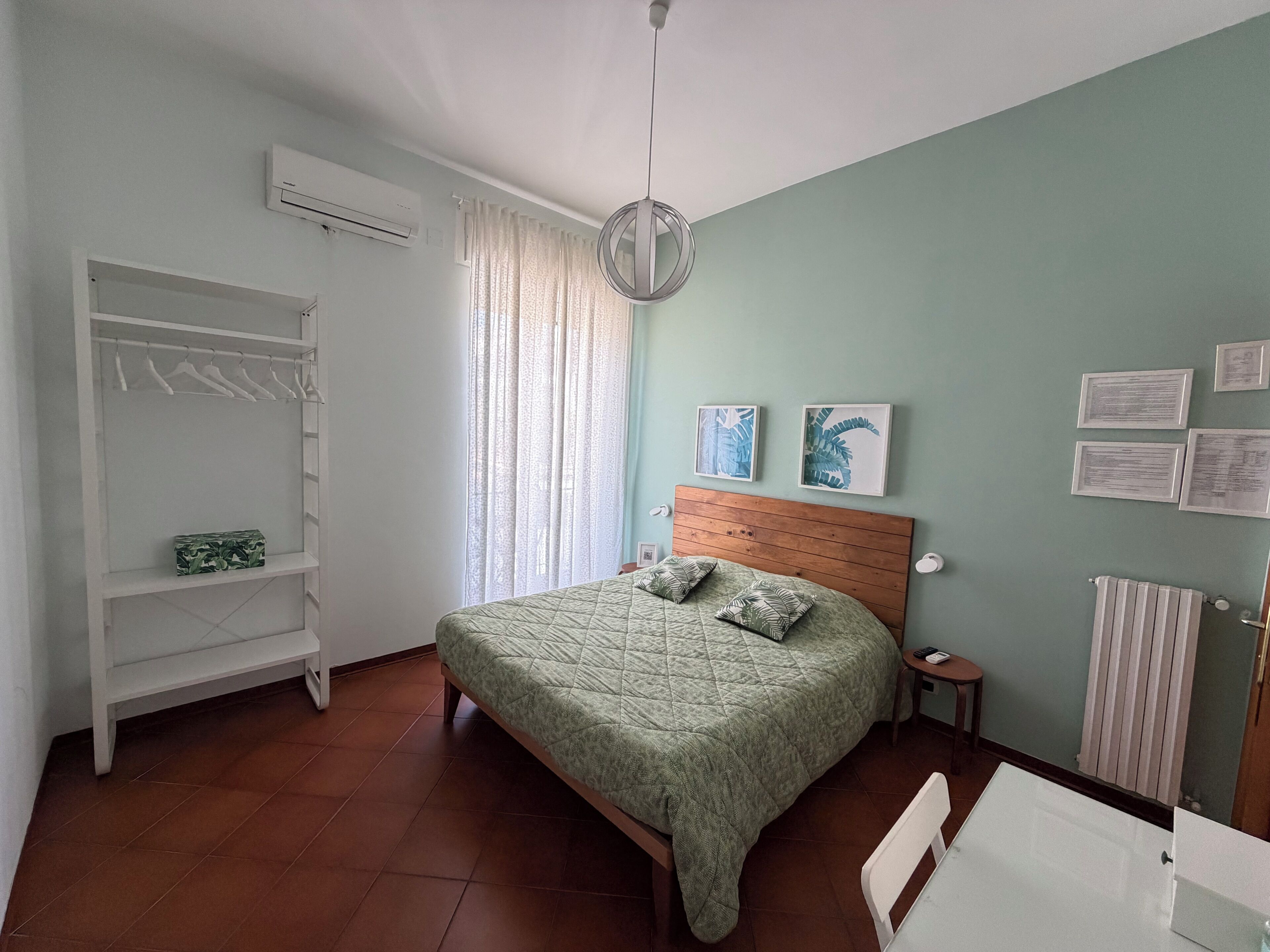Une chambre à coucher avec un lit, une armoire, un radiateur et une fenêtre avec des rideaux.