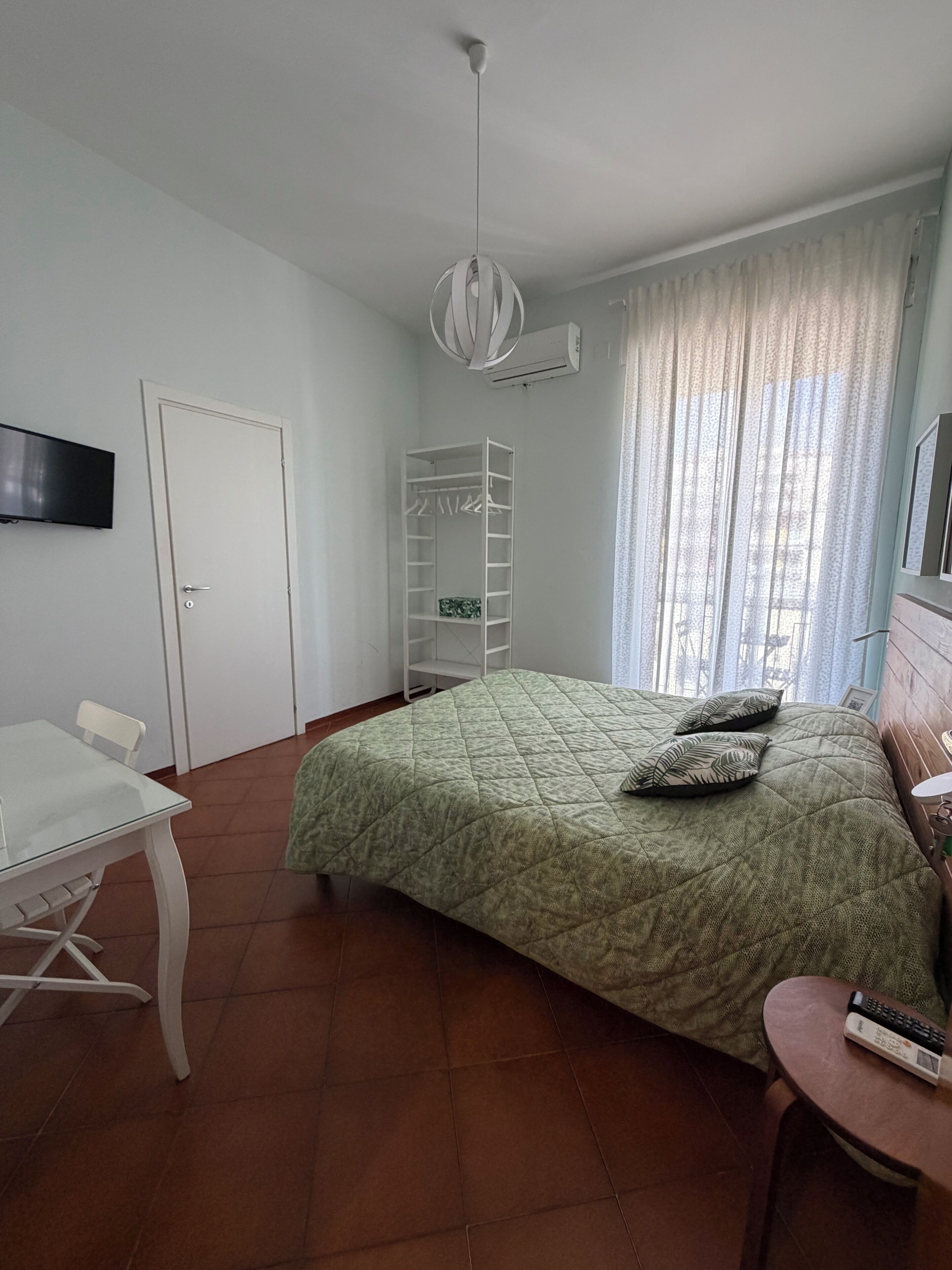 Un dormitorio con cama, televisor, armario y escritorio.