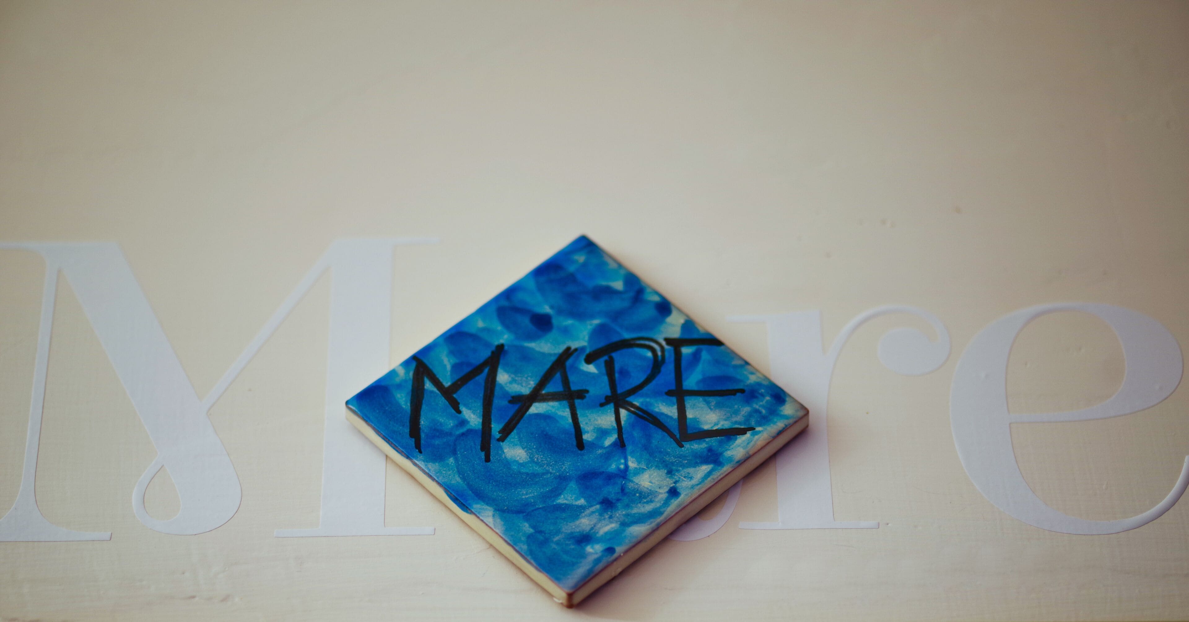 A notebook with the word "MARE" written on it, placed on a surface with large letters partially visible.