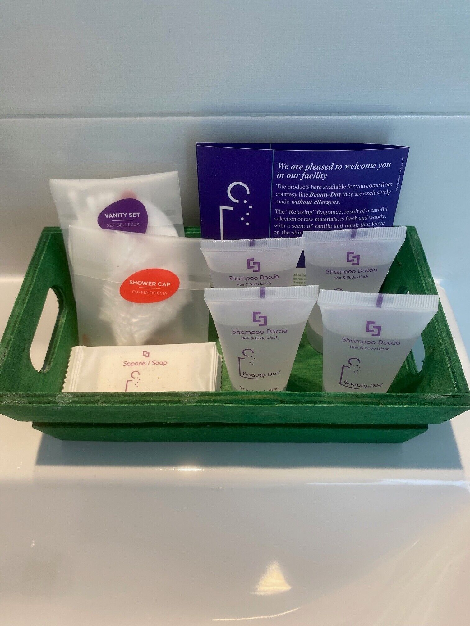 A green tray containing a vanity set, a shower cap, and multiple bottles of shampoo and soap.