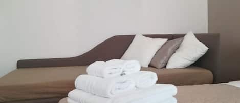 A hotel room with a bed, pillows, and neatly folded towels.