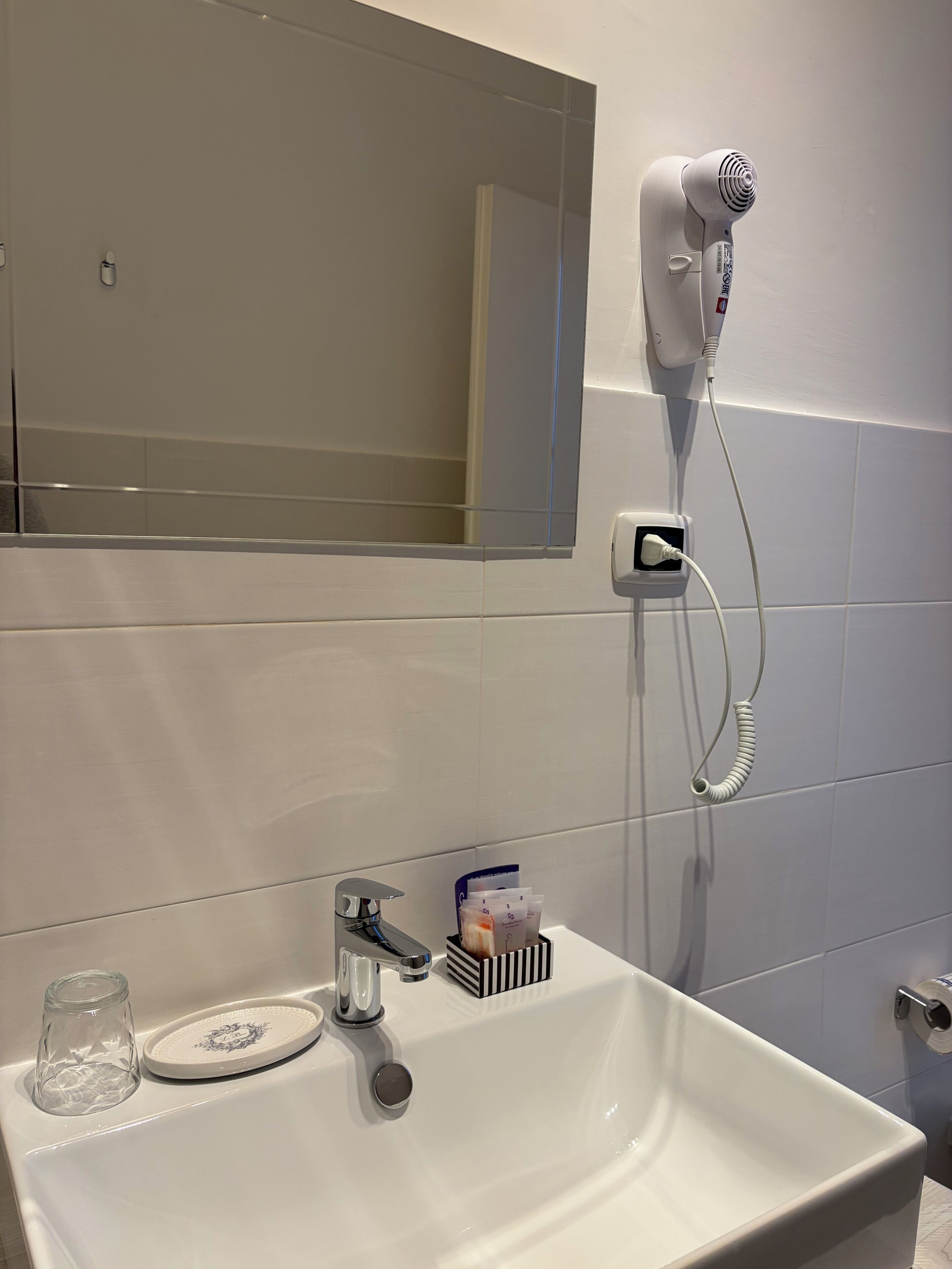 A bathroom with a white sink, a mirror, a hairdryer, and a towel rack.