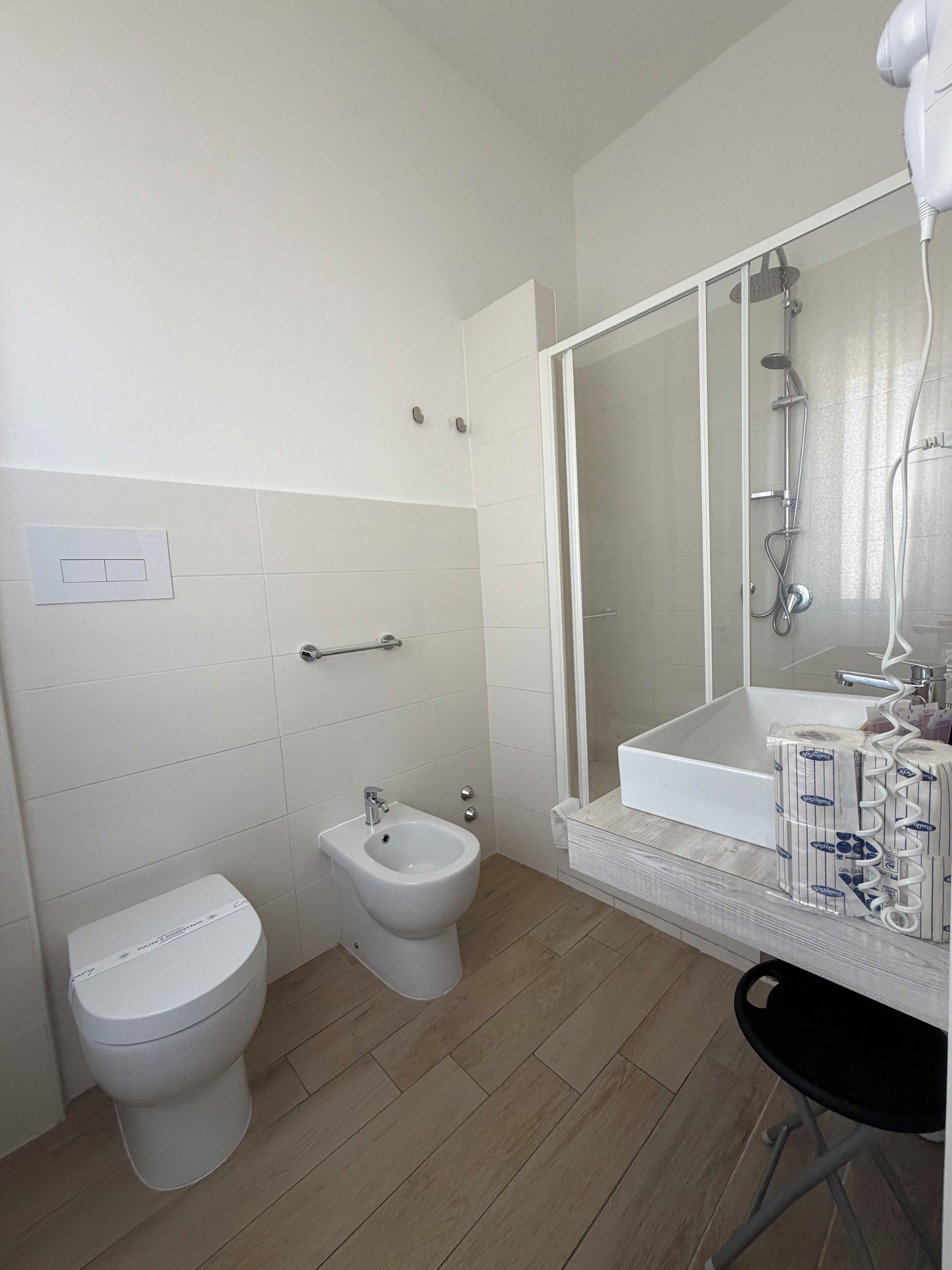 A bathroom with a toilet, bidet, bathtub, and a mirror with a showerhead.
