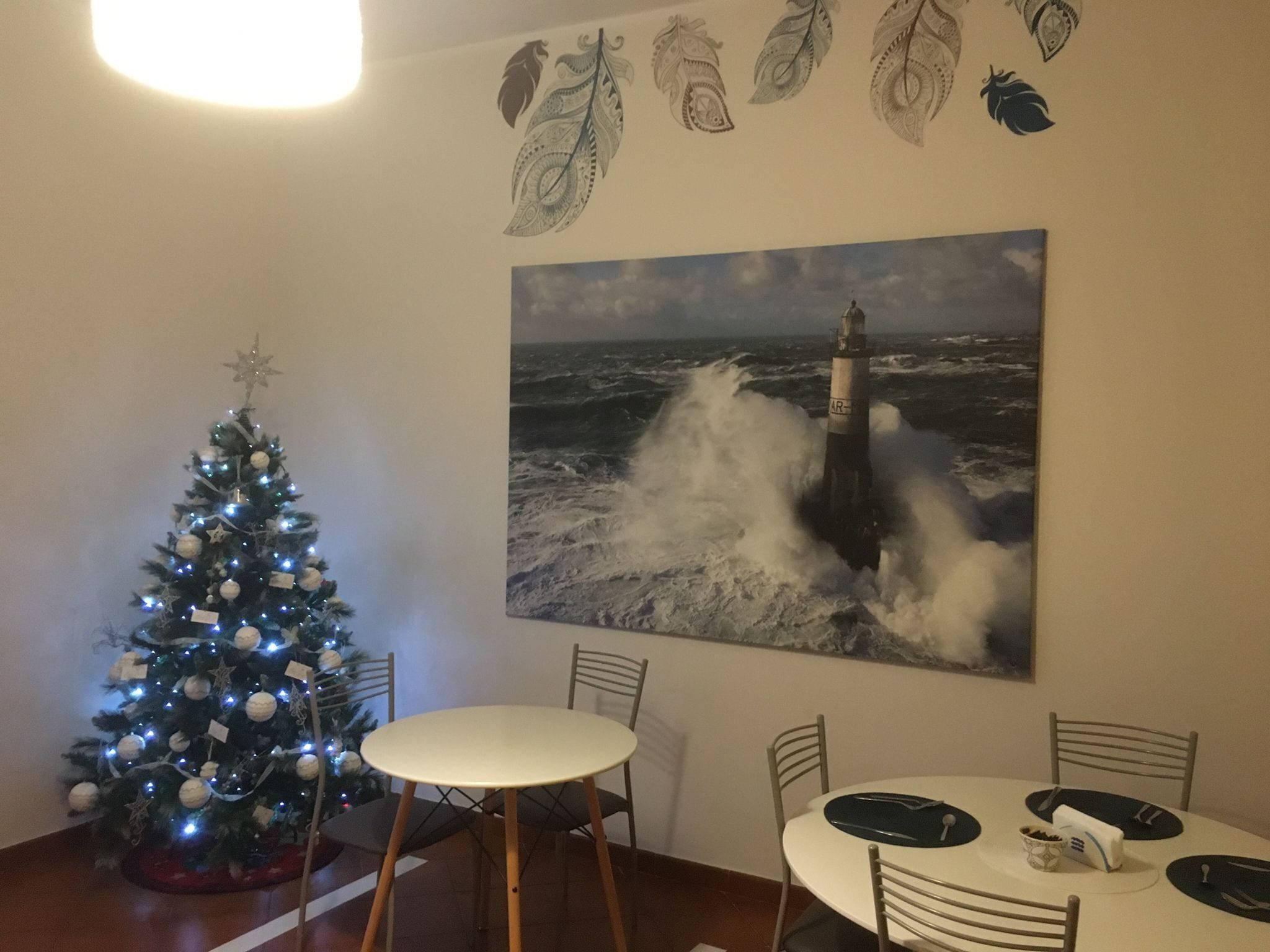A dining area with a round table, chairs, and a Christmas tree with lights.