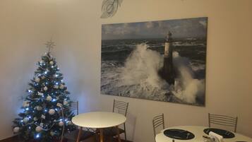 A dining area with a round table, chairs, and a Christmas tree with lights.