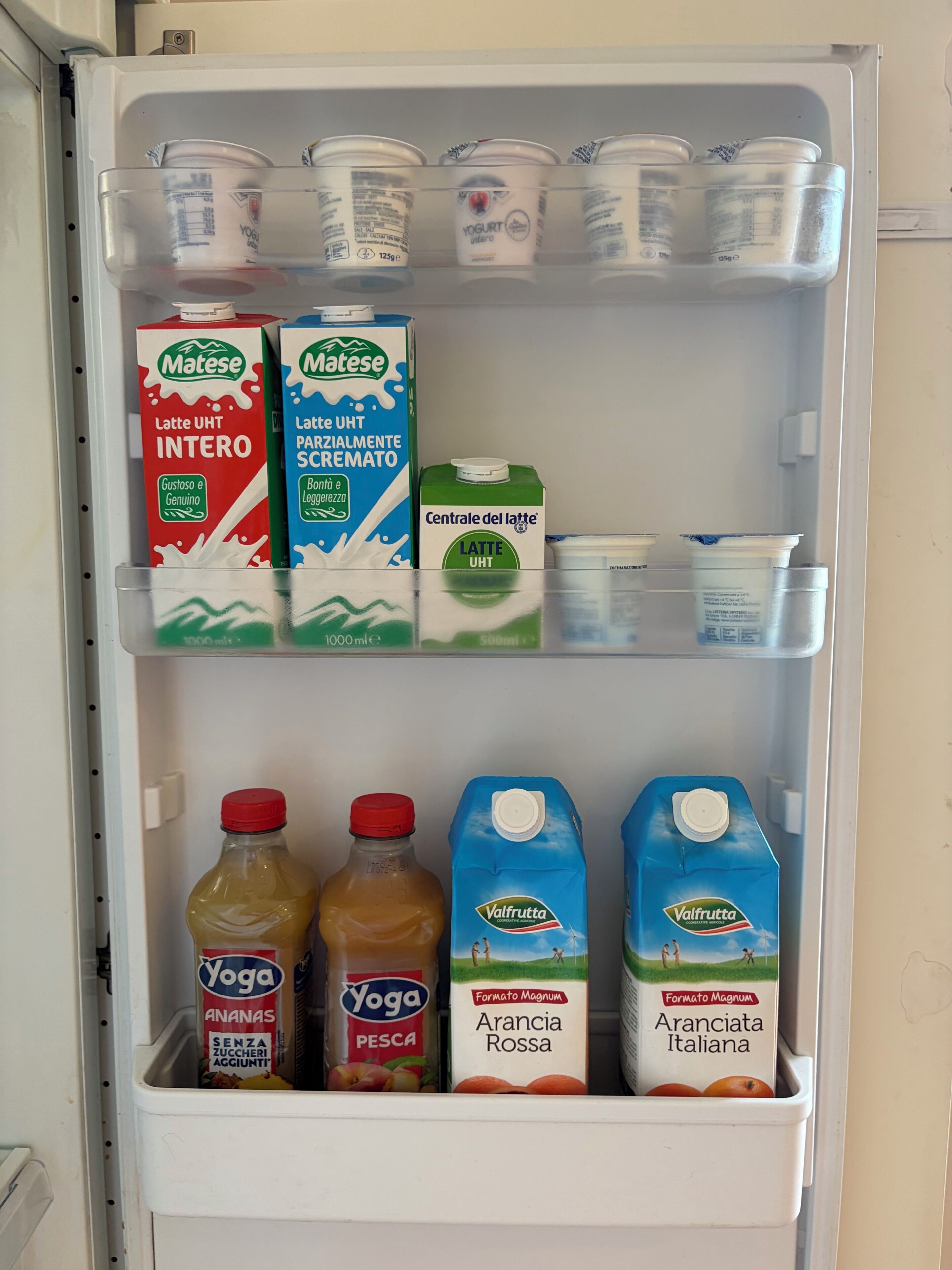 A refrigerator stocked with various dairy products including yogurts, milk, and juice.