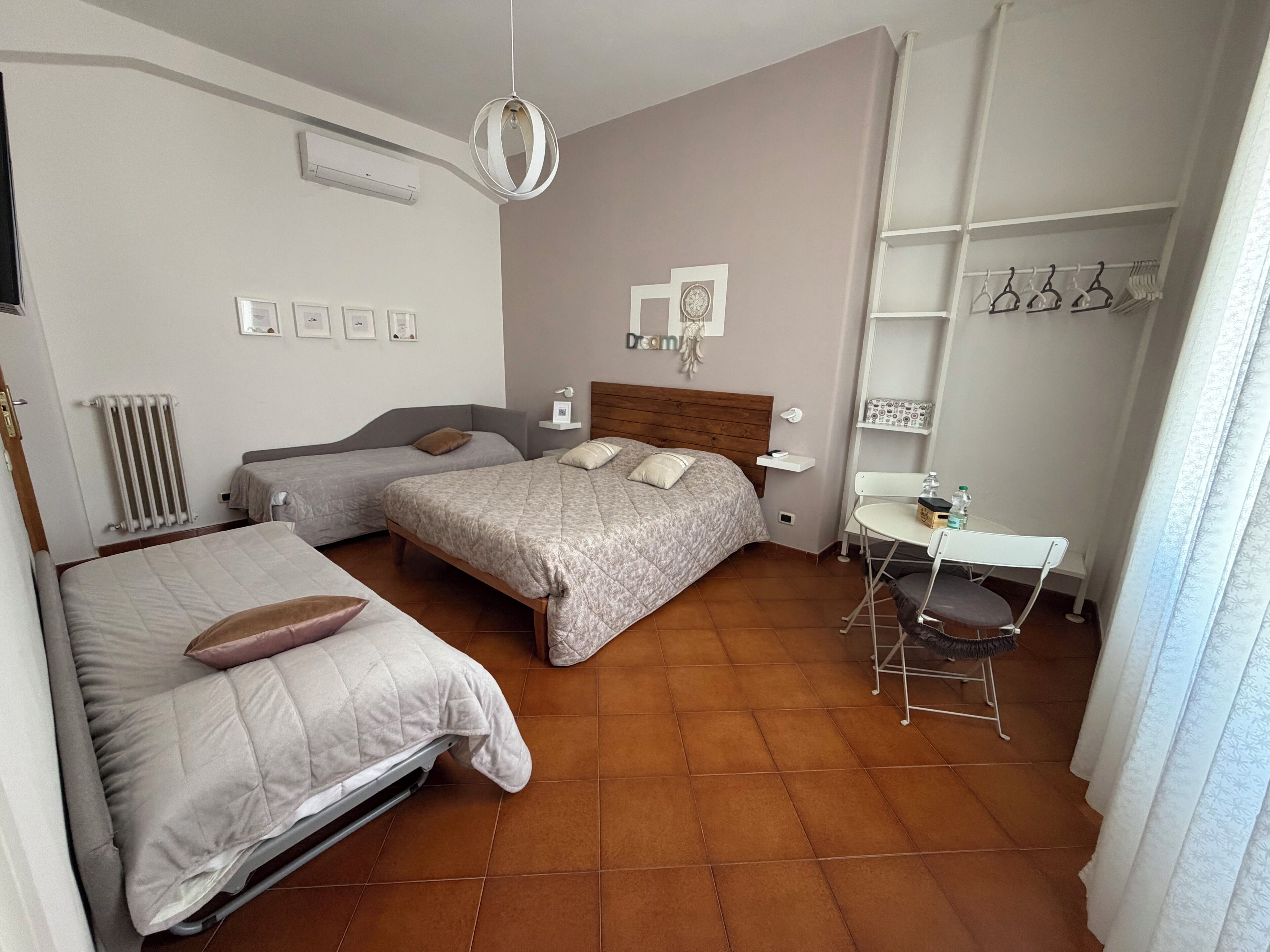 Un dormitorio con dos camas, un escritorio, una silla, un radiador y una lámpara colgante.