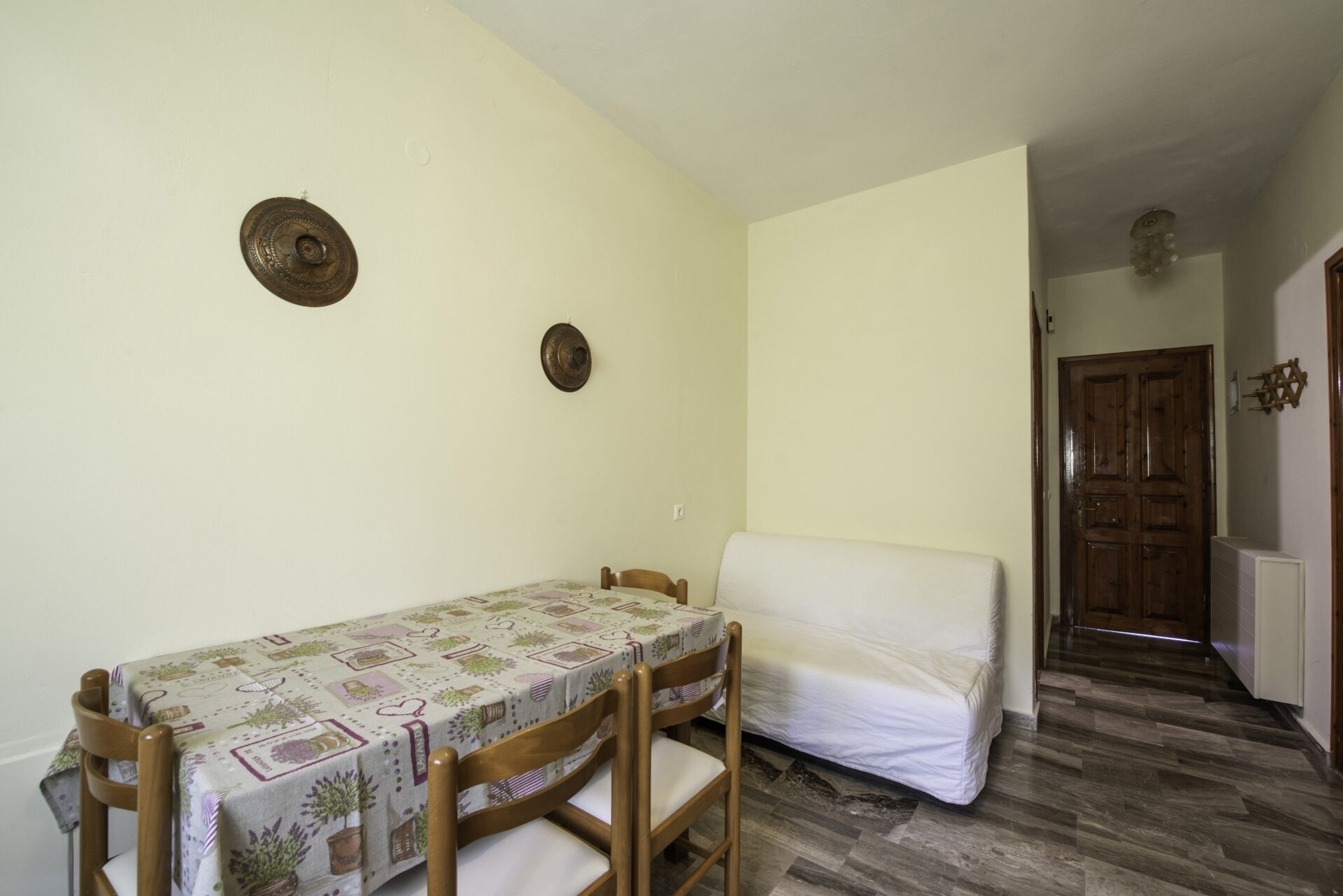 Una habitación pequeña y acogedora con una mesa de comedor y sillas, un sofá y una puerta de madera.