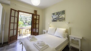 A bedroom with a bed, a painting, a table, and a chair.