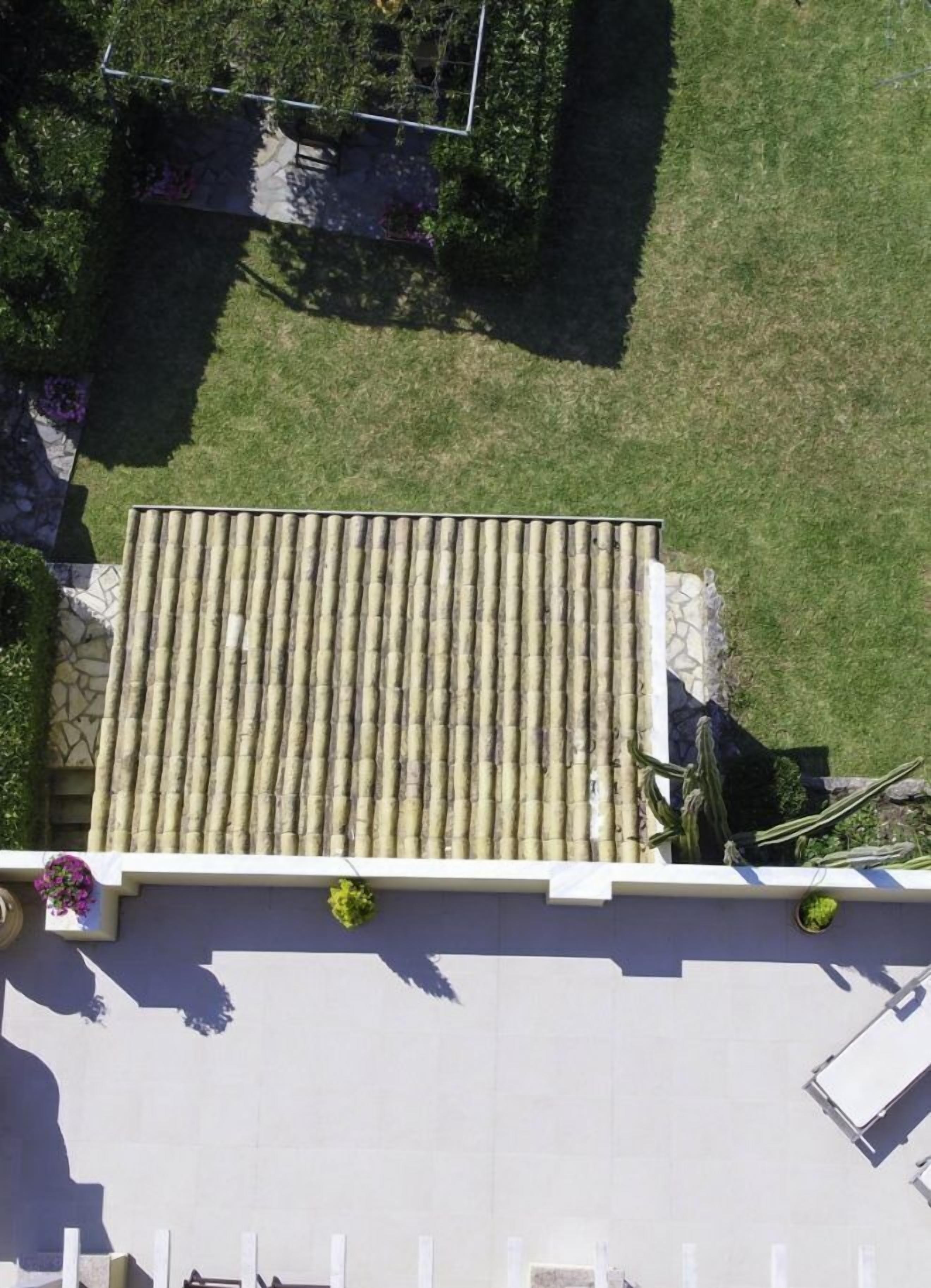 A rooftop terrace with a tiled roof, a small garden area, and a white railing.