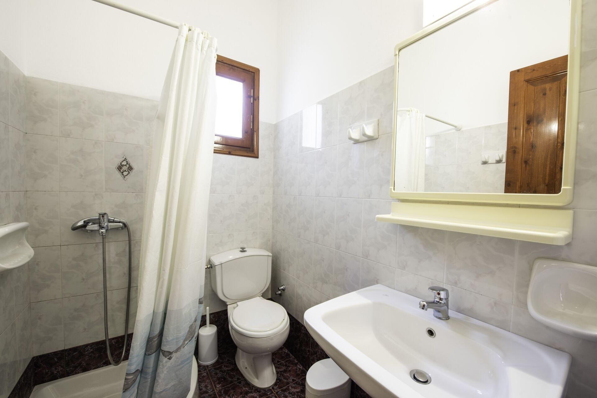 A bathroom with a shower, toilet, sink, and mirror.