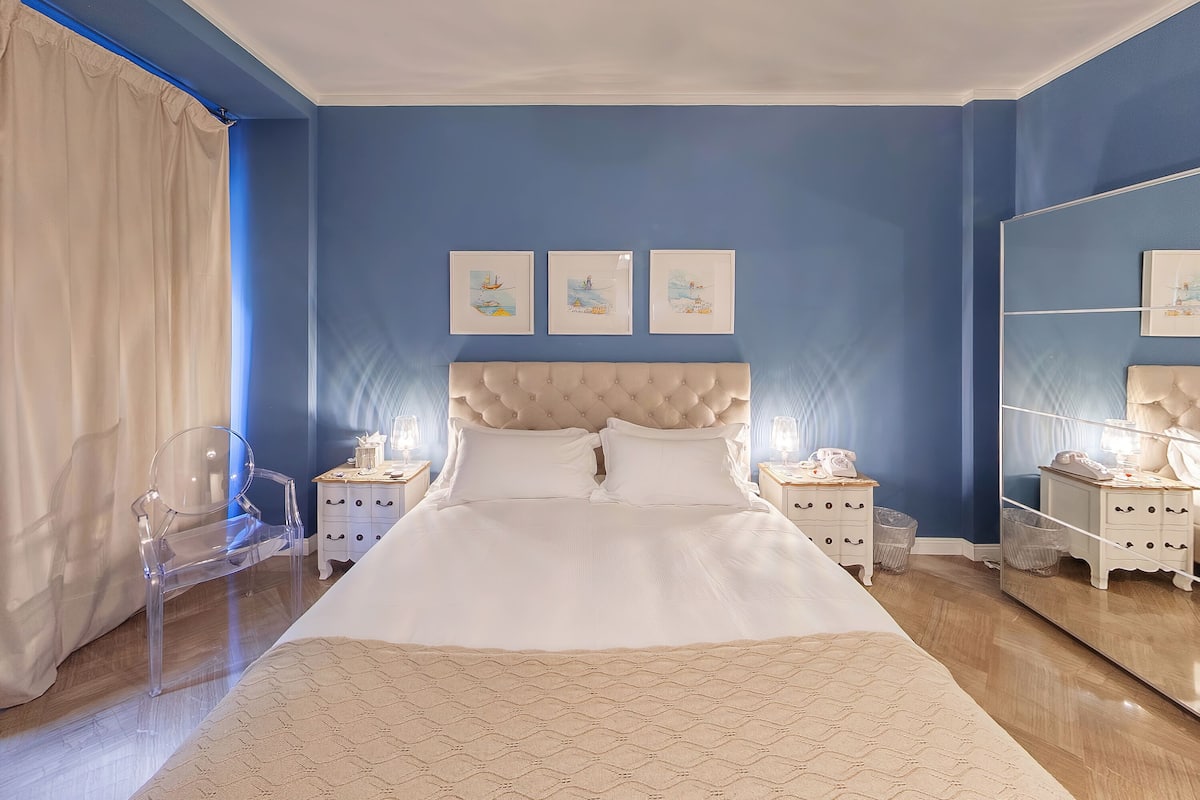 A bedroom with a large bed, a headboard, bedside tables, and wall art.