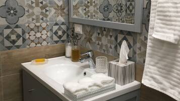 Un baño con un lavamanos blanco, un espejo y azulejos estampados en las paredes.