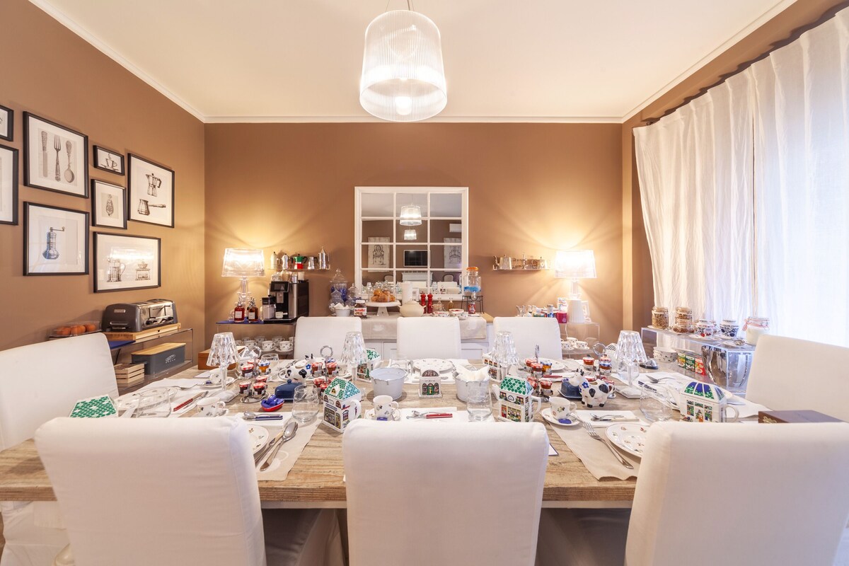 A dining area with a long table set for a meal, surrounded by white chairs.