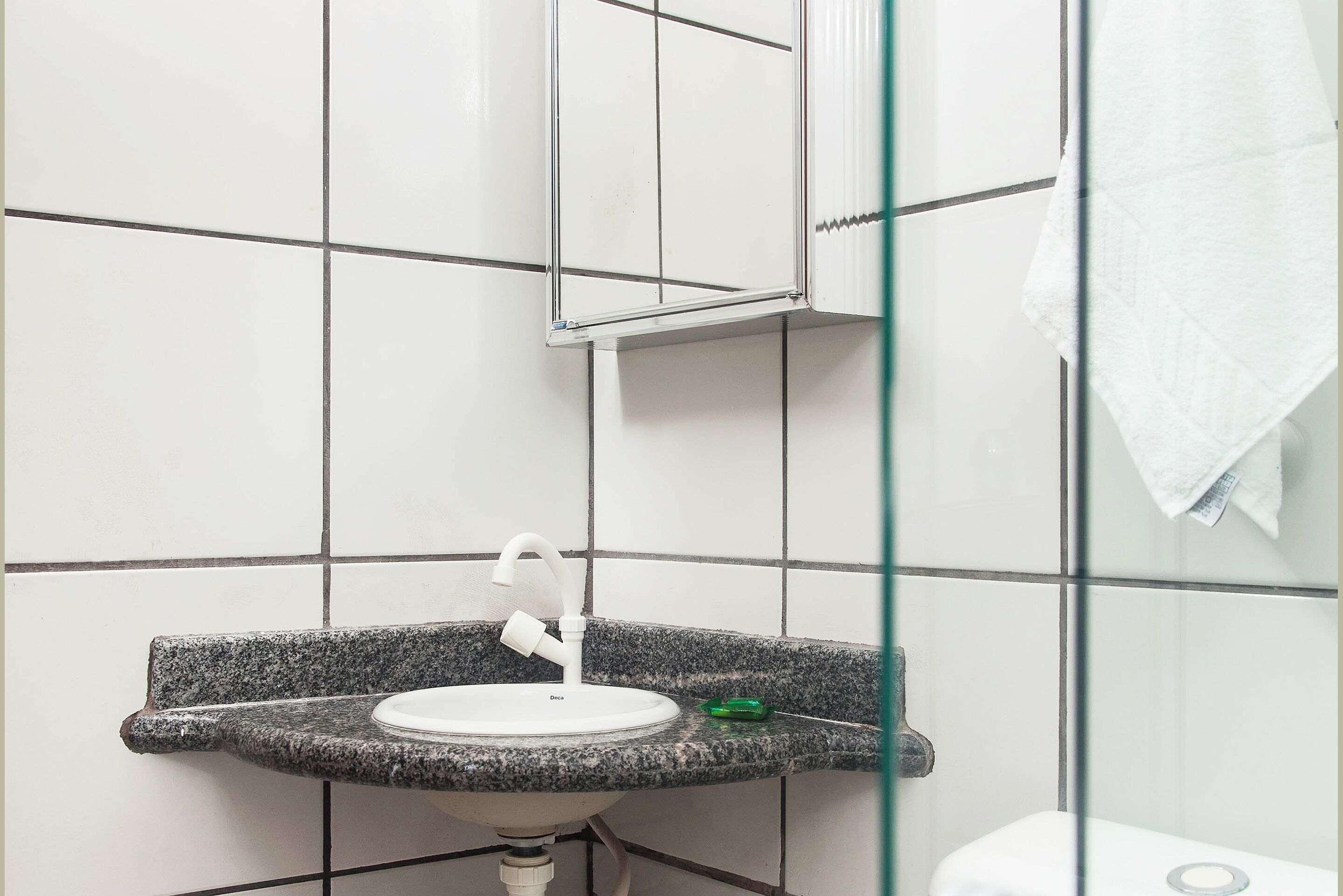 Un baño con lavamanos de encimera de granito, inodoro blanco y cabina de ducha de vidrio.
