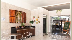 A cafe with a wooden counter, metal chairs, and a glass door leading to the outside. - Pousada Recanto do Mucugê (Porto Seguro)