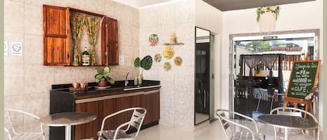 Una cafetería con mostrador de madera, sillas de metal y puerta de cristal que da al exterior.