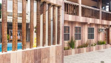 Un edificio con piscina, columnas de madera y un balcón.