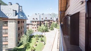 Ein Innenhof mit einem hölzernen Balkon, der auf ein Gebäude mit zahlreichen Fenstern und einer Steinaußenwand blickt.