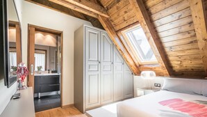 Ein Schlafzimmer mit schrägem Dach, einem Bett, einem Nachttisch und einer Kommode.