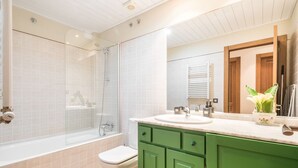 Ein Badezimmer mit einer Duschkabine aus Glas, einer weißen Toilette und grünen Schränken.