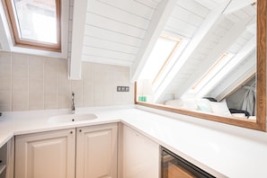 Une salle de bain moderne avec une lucarne, des carreaux blancs, un lavabo et un miroir.