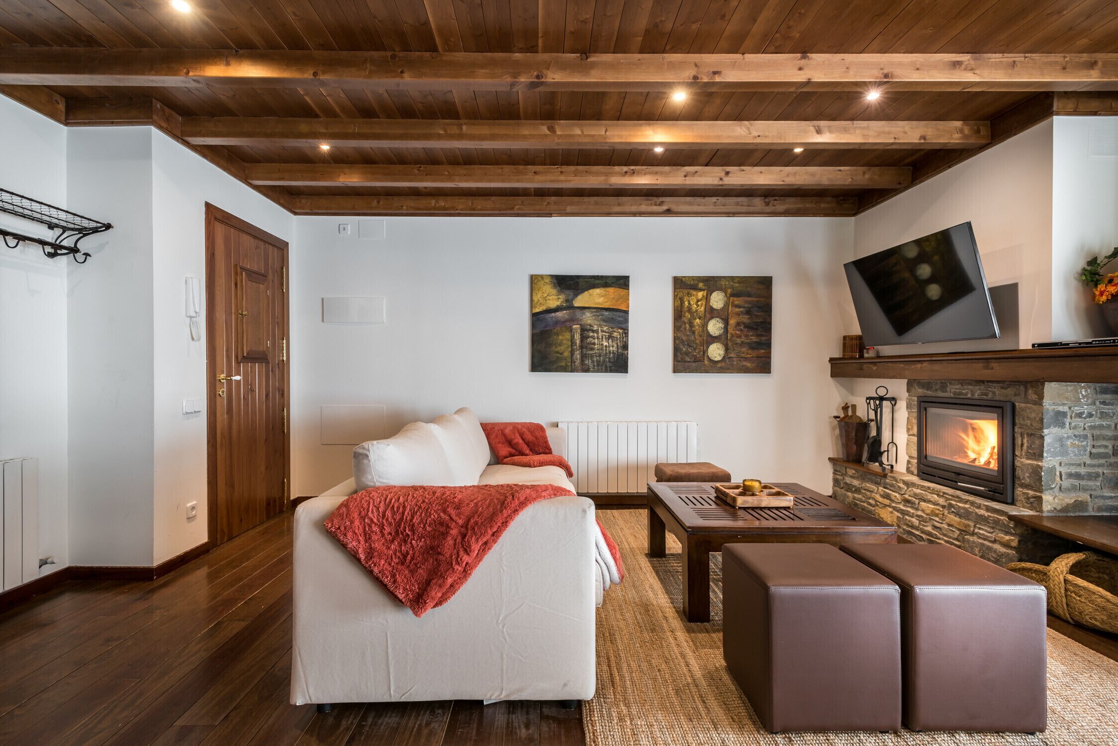 A cozy living room with a fireplace, a sofa, a coffee table, and a TV.