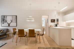 A modern kitchen with a white countertop, a dining area with a white table and brown chairs, and a large framed deer picture on the wall. - Airoto by Totiaran, located few steps to ski gondola in Baqueira 2 bedroom modern apartment (Baqueira)