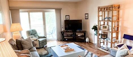 Una sala de estar con un sofá, una mesa de centro, un televisor y una estantería.