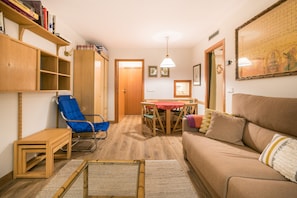Cozy living space with a wooden bookshelf, armchair, and sofa, plus a dining area with a table and chairs.