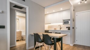 Una cucina moderna con zona pranzo, pavimento in legno e mobili bianchi.