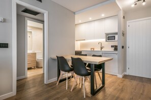 Una cocina moderna con zona de comedor, suelo de madera y armarios blancos.