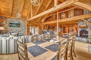 A spacious wooden interior with a dining area, stone walls, and a fireplace. - Beach Front Estate Custom Timber Frame Home on Cleveland Beach 72 (Hubbards)