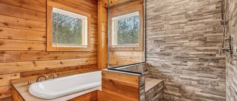A wooden cabin bathroom with a bathtub, a shower, and a large mirror.