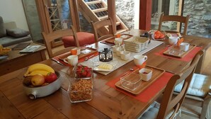 Una mesa de madera dispuesta para el desayuno, con frutas, cereales y tazas de café.