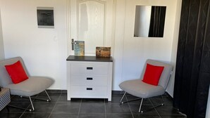 A hotel room with a bed, two armchairs, a white dresser, a mirror, and a door. - MALAKA F1 of charm ........ (LE MOULE)