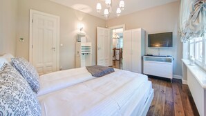 A bedroom with a large bed, a TV, a wardrobe, and a chandelier.
