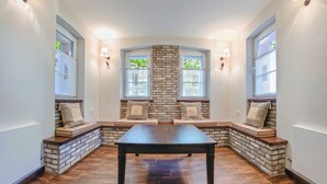 A room with a dark wooden table, built-in seating with cushioned benches, and a brick accent wall.