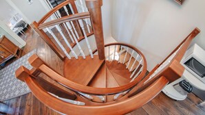A wooden spiral staircase with white railings and a wooden handrail.