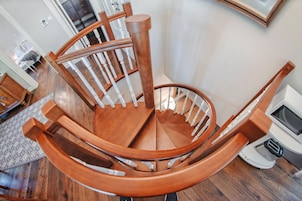 Una escalera en espiral de madera con barandillas blancas y un pasamanos de madera.