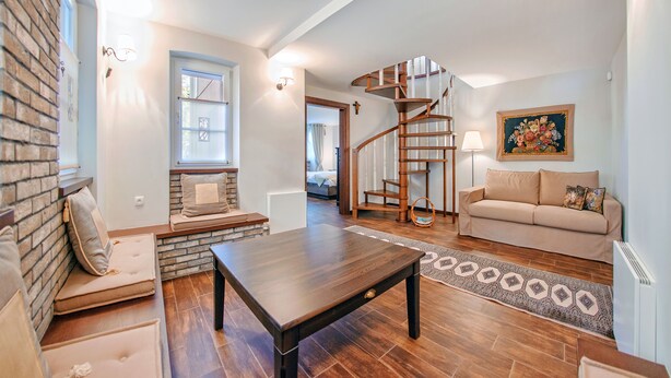 A living room with a wooden staircase, a sofa, a coffee table, and a rug.
